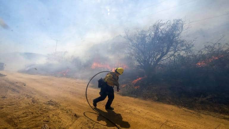 A firefighter runs as the wind blows at the Apple Fire in Banning, California. The National Weather Service said “dangerously hot conditions” were expected to continue because of high pressure over much of Southern California. (Image courtesy: AP)