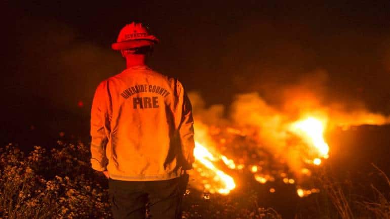 A firefighter watches a brush fire at the Apple Fire in Banning, California. A huge smoke plume was visible for miles around and contributed to poor air quality. (Image courtesy: AP)