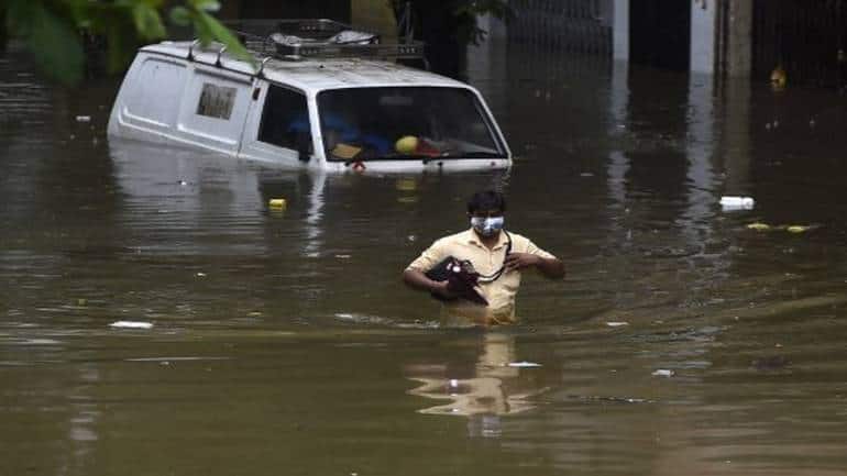 A man wades through a flooded street next to a partially submerged van following heavy monsoon rains (Image: AFP)
