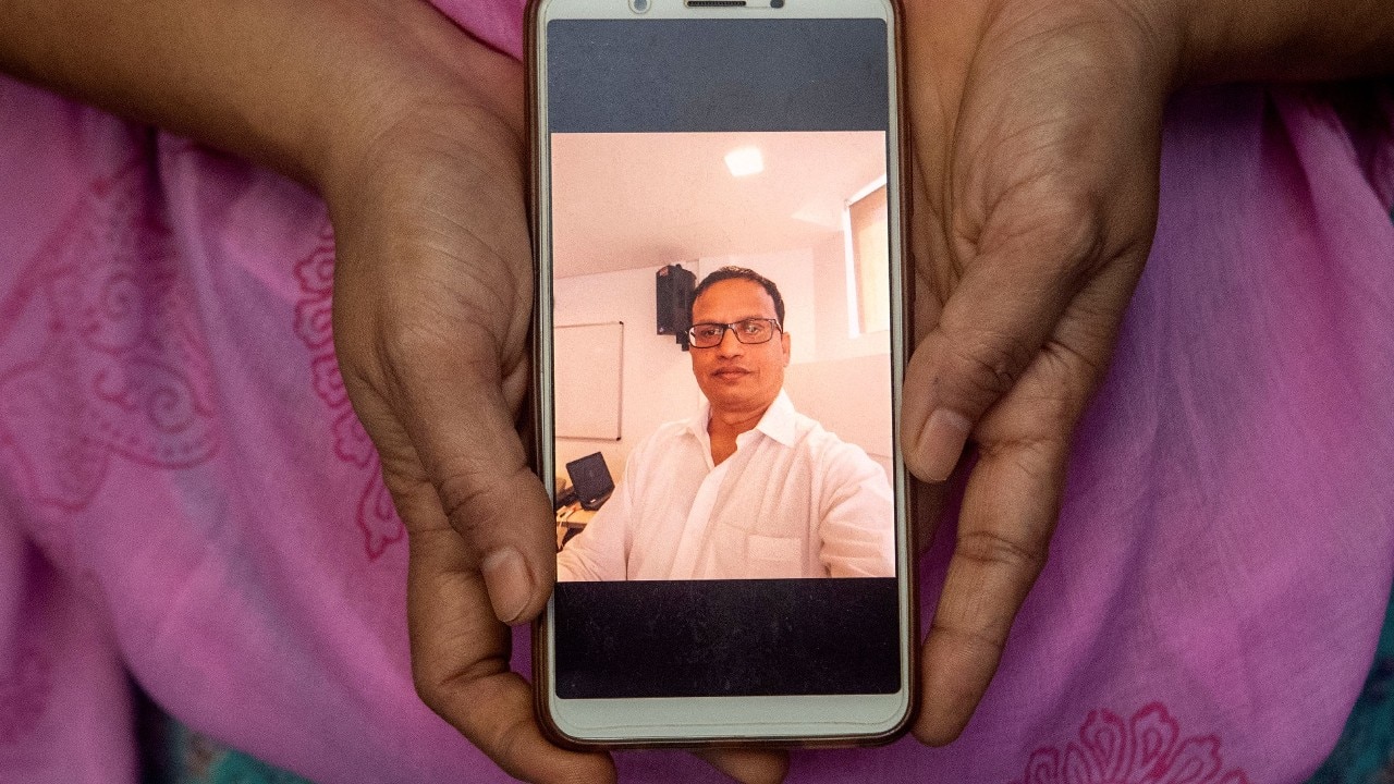 Sunita Patil, 44, a housewife, shows a picture on her phone of her husband Vivek Patil, a music teacher, who died due to the coronavirus disease, as she poses for a photograph, in Mumbai, India, September 27. Vivek died suddenly at home in Mumbai before a bed at a local hospital became available. The next morning, Sunita said, municipal workers came to the house shouting for them to come outside to be taken to a quarantine centre. "They were not sensitive to the fact that there has been a death in the family just a day back, and we are in mourning," she said. "I have two young daughters with almost no income. It will be very hard for us to live without my beloved husband." (Image: Reuters) Sunita Patil, 44, a housewife, shows a picture on her phone of her husband Vivek Patil, a music teacher, who died due to the coronavirus disease, as she poses for a photograph, in Mumbai, India, September 27. Vivek died suddenly at home in Mumbai before a bed at a local hospital became available. The next morning, Sunita said, municipal workers came to the house shouting for them to come outside to be taken to a quarantine centre. "They were not sensitive to the fact that there has been a death in the family just a day back, and we are in mourning," she said. "I have two young daughters with almost no income. It will be very hard for us to live without my beloved husband." (Image: Reuters)