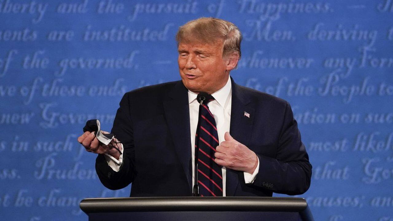 President Donald Trump holds out his face mask during the first presidential debate at Case Western University and Cleveland Clinic, in Cleveland, Ohio, September 29, 2020. (AP Photo)