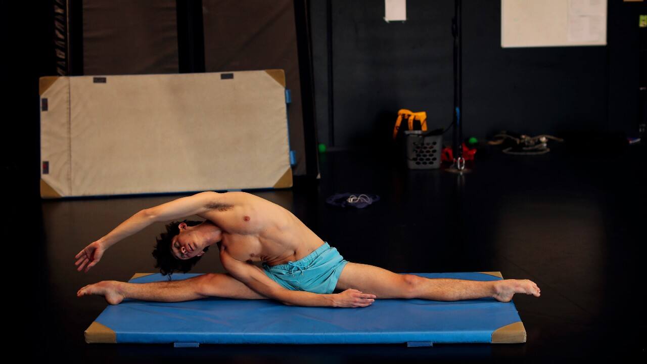 For safety reasons amid the pandemic, Venezuelan school director Reynaldo Ramperssad had to cut the number of students by 25 percent, creating “bubbles” where only a few work together in a small group and do online theory classes. A student stretches before a class at the Superior School of Circus Arts (ESAC) in Brussels, September 23. (Image: AP)