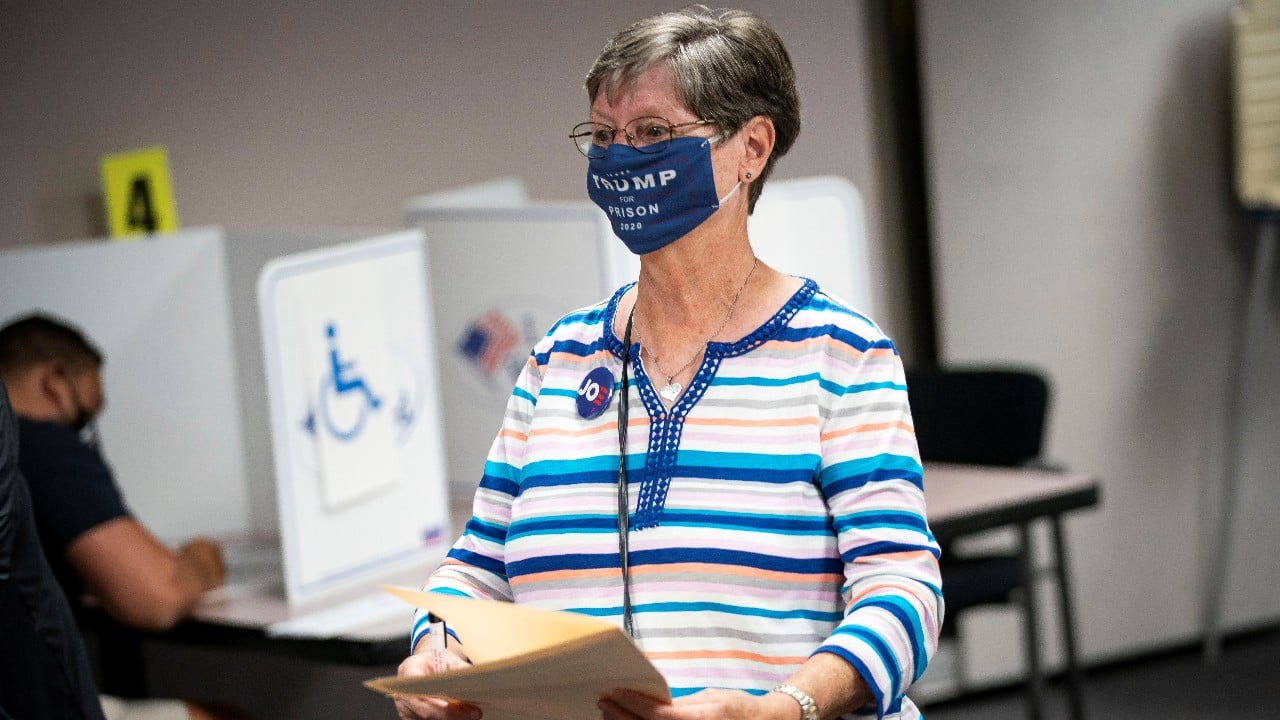 A woman wears a &quot;Trump for Prison&quot; face mask as she walks to cast her ballot at an early voting site at the Fairfax County Government Centre in Fairfax, Virginia. (Image: Reuters)