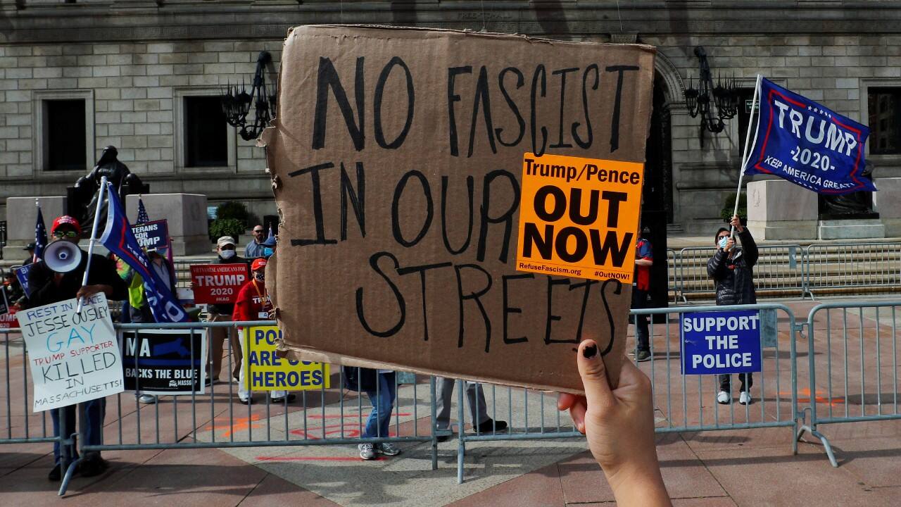 A counter-protestor holds up sign in front of demonstrators at the &quot;Peaceful Protest Against Democrat Violence&quot; sponsored by Super Happy Fun America in Boston, Massachusetts, U.S., October 18. (Image: Reuters)