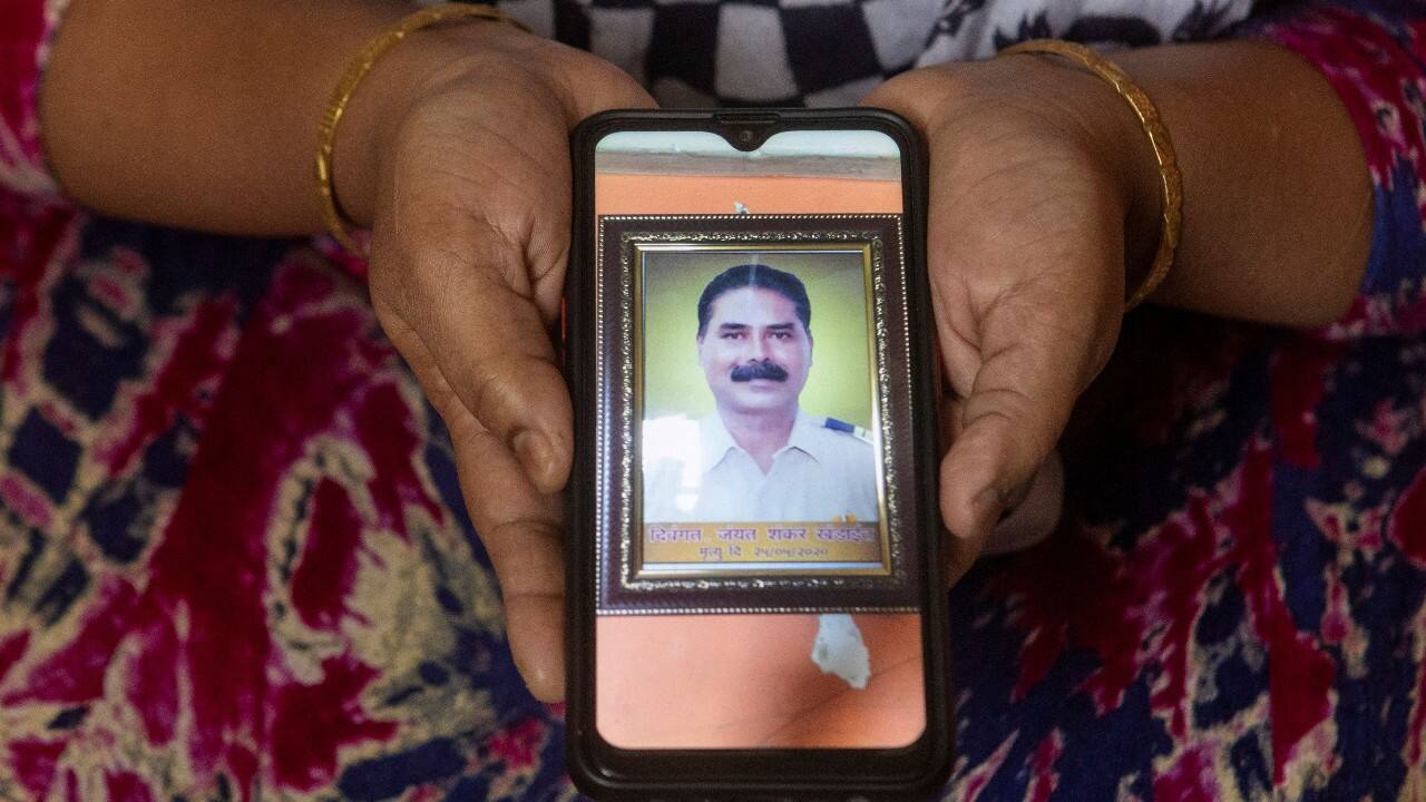 Rekha Khandait, 38, a housewife, shows a picture on her phone of her husband Jayant Khandait, 58, a police head constable, who died due to the coronavirus, as she poses for a photograph, in Mumbai, India, September 27. "I know my husband has passed away but I can still feel his presence. I can't believe that six months have passed. I still haven't told our son about his father's death," said Khandait. (Image: Reuters) Rekha Khandait, 38, a housewife, shows a picture on her phone of her husband Jayant Khandait, 58, a police head constable, who died due to the coronavirus, as she poses for a photograph, in Mumbai, India, September 27. "I know my husband has passed away but I can still feel his presence. I can't believe that six months have passed. I still haven't told our son about his father's death," said Khandait. (Image: Reuters)