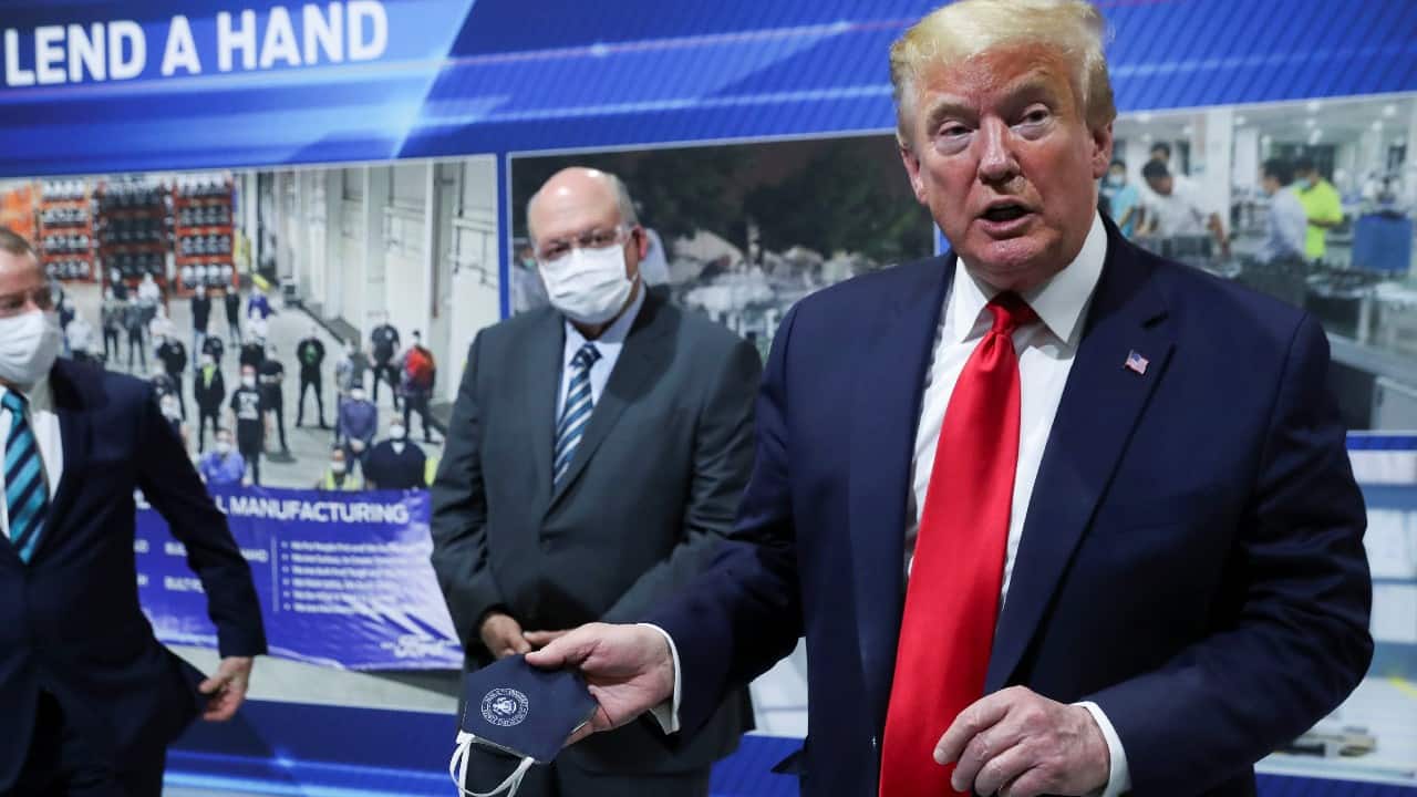  Trump holds a protective face mask with a presidential seal on it that he said he had been wearing earlier in his tour to a Ford plant in Michigan but took it off in front of the cameras flouting precautionary measures. (Image: Reuters)