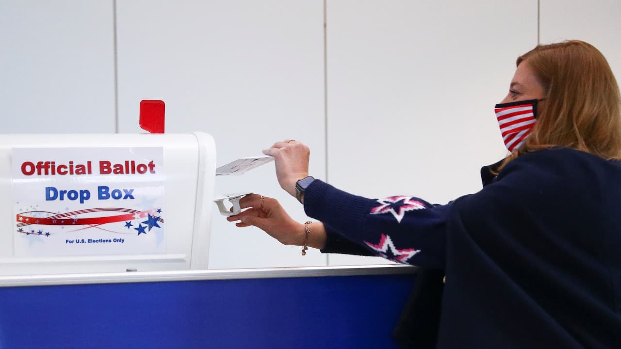 Patricia Wynn wearing a protective mask casts an early ballot for the US presidential election at the country's embassy in London on October 13 (Image: Reuters)