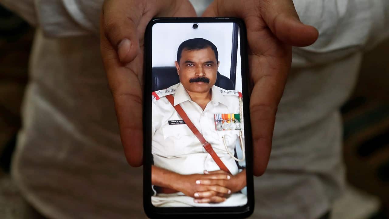 Rahul Adhav, 26, a pharmacist, shows a picture on his phone of his father Bhaginath Jagannath Adhav, a police officer, who died due to the COVID-19, as he poses for a photograph, in Mumbai, India, September 28. "Life has become lonely since my father passed away, no one can take his place in the family. My dad did his best while on duty urging the general public to maintain social distancing etc. I request people to maintain social distancing and co-operate with the police. The police are doing their best to serve you. I also request that the government to provide financial support to families of police who died while serving the people in the pandemic," said Adhav. (Image: Reuters) Rahul Adhav, 26, a pharmacist, shows a picture on his phone of his father Bhaginath Jagannath Adhav, a police officer, who died due to the COVID-19, as he poses for a photograph, in Mumbai, India, September 28. "Life has become lonely since my father passed away, no one can take his place in the family. My dad did his best while on duty urging the general public to maintain social distancing etc. I request people to maintain social distancing and co-operate with the police. The police are doing their best to serve you. I also request that the government to provide financial support to families of police who died while serving the people in the pandemic," said Adhav. (Image: Reuters)
