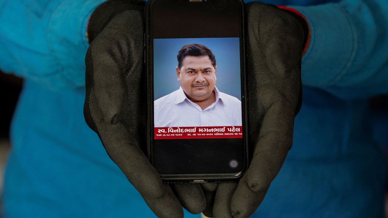 Dixit Vinodbhai Patel, 19, a student, shows a picture on his phone of his father Vinodbhai Maganbhai Patel, 54, a shopkeeper, who died due to the COVID-19, as he poses for a photograph, in Ahmedabad, India, September 25. "After my father's death, all responsibility is on my head as my father was the only earning member in our family. Presently I try to fulfil all family requirements, I try to be a good son, a loving brother. My college is closed at the movement, but when it starts, I will quit my studies to take care of my family," Dixit said. (Image: Reuters) Dixit Vinodbhai Patel, 19, a student, shows a picture on his phone of his father Vinodbhai Maganbhai Patel, 54, a shopkeeper, who died due to the COVID-19, as he poses for a photograph, in Ahmedabad, India, September 25. "After my father's death, all responsibility is on my head as my father was the only earning member in our family. Presently I try to fulfil all family requirements, I try to be a good son, a loving brother. My college is closed at the movement, but when it starts, I will quit my studies to take care of my family," Dixit said. (Image: Reuters)