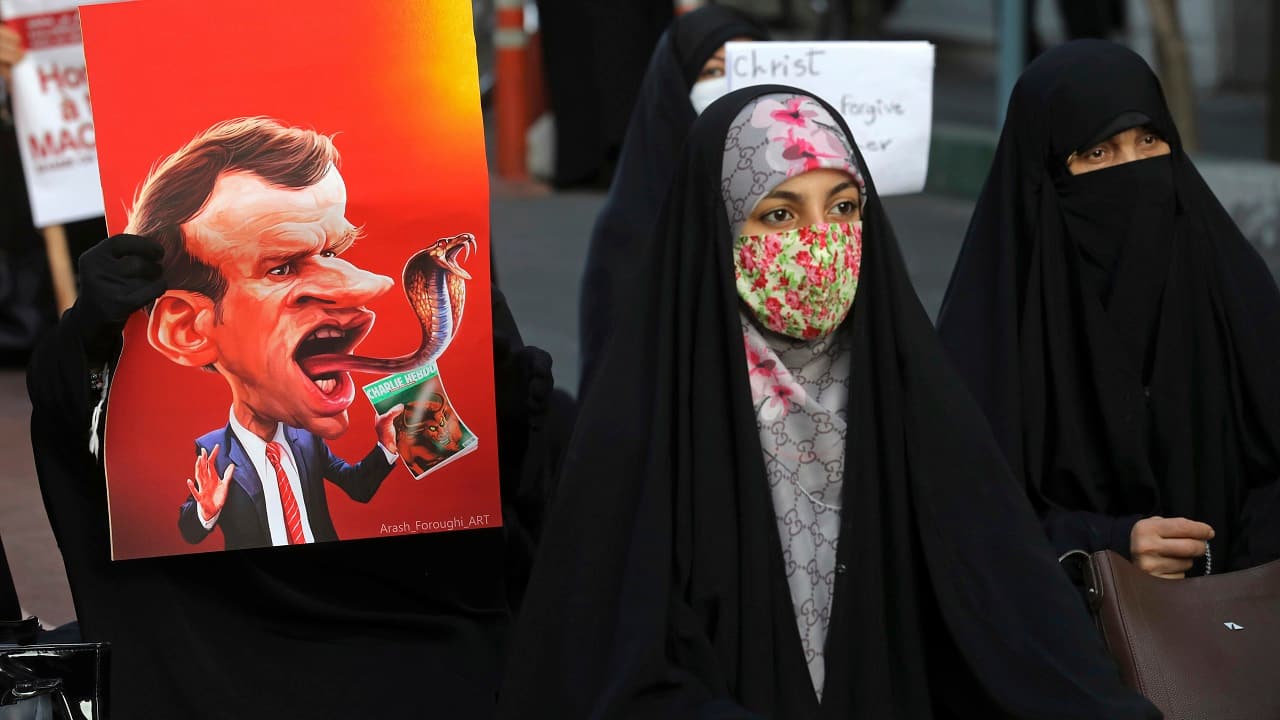 Iranian protesters hold defaced pictures of French President Emmanuel Macron during a protest in front of the French Embassy in Tehran, Iran on October 28, 2020. (Image: AP Photo/Ebrahim Noroozi)