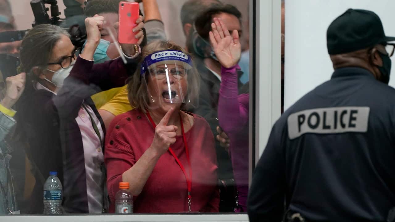 People yell as they look through the windows of the central counting board as police were helping to keep others from entering due to overcrowding in Detroit. (Image: AP/Carlos Osorio)