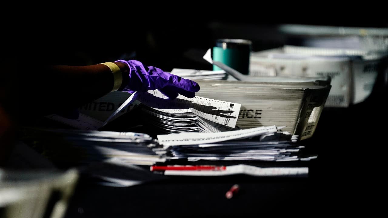 Election personnel handle ballots as vote counting in the general election continues at State Farm Arena in Atlanta. (Image: AP/Brynn Anderson)