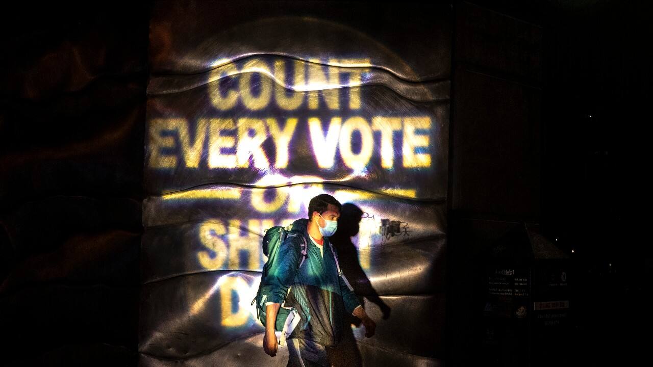A man walks through a projected election slogan during protests following the November 3 presidential election in Portland, Ore. (Image: AP/Paula Bronstein)