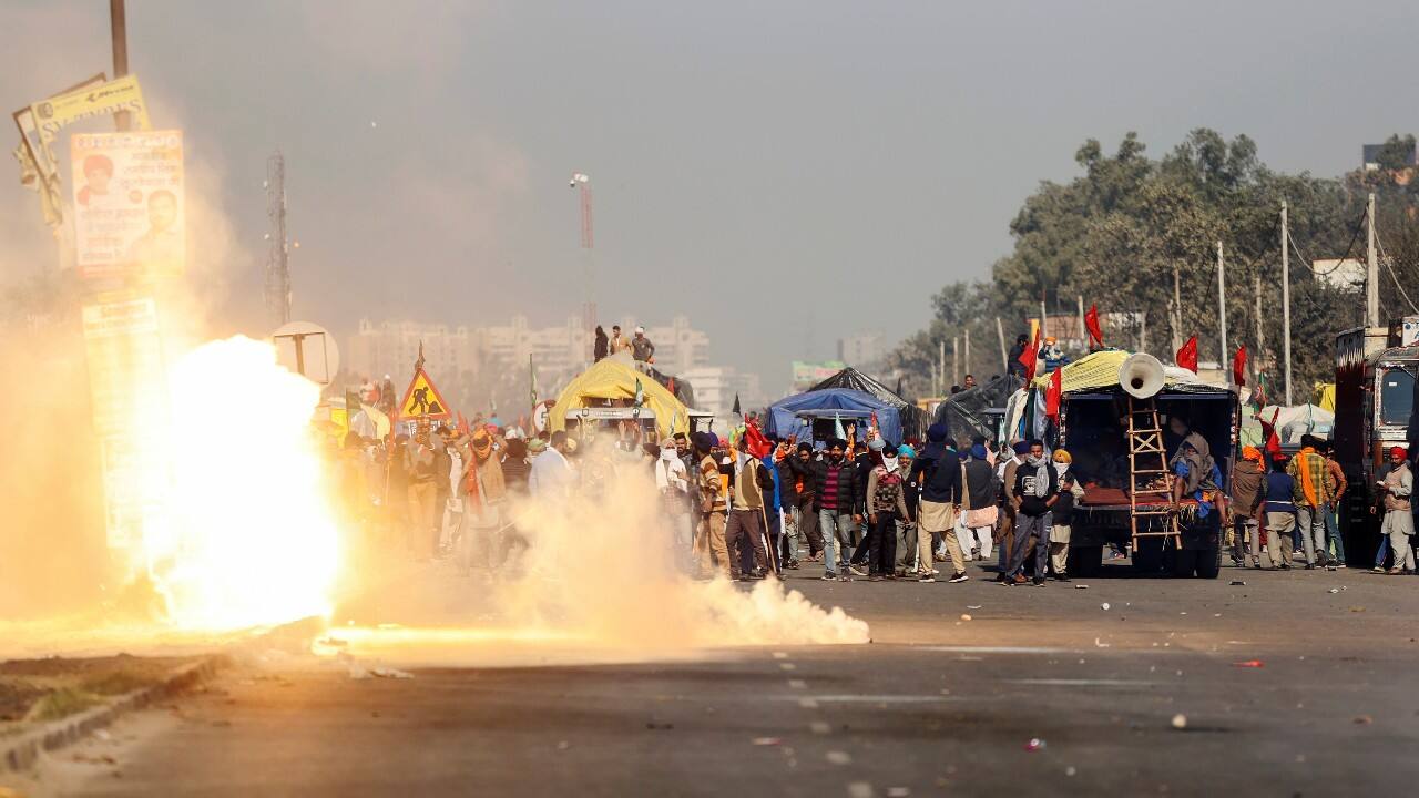 Flames emerge from tear gas fired by the police to stop farmers opposing the newly passed farm bills from entering the national capital at Singhu border on November 27. (Image: Reuters)