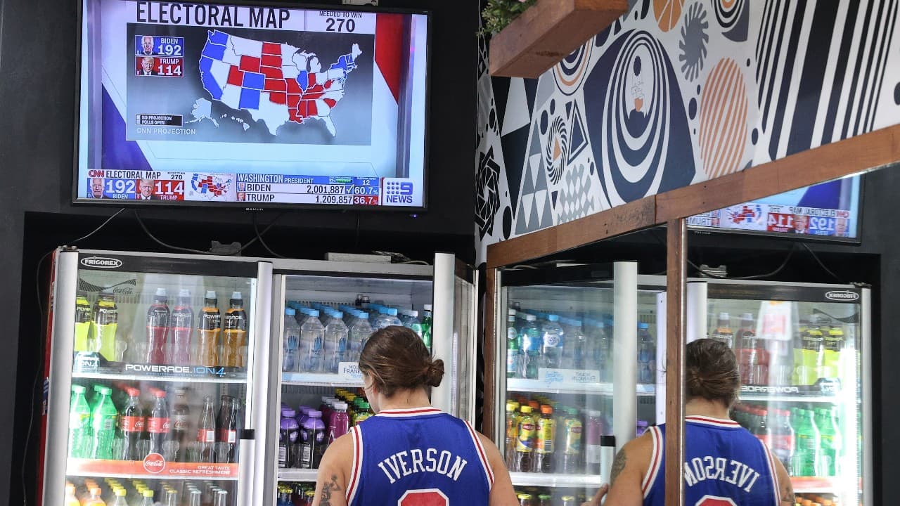 Results come in for the U.S. presidential election between President Donald Trump and Democratic presidential nominee Joe Biden, as seen from a store as a customer shops in Sydney, Australia, November 4. (Image: Reuters) 