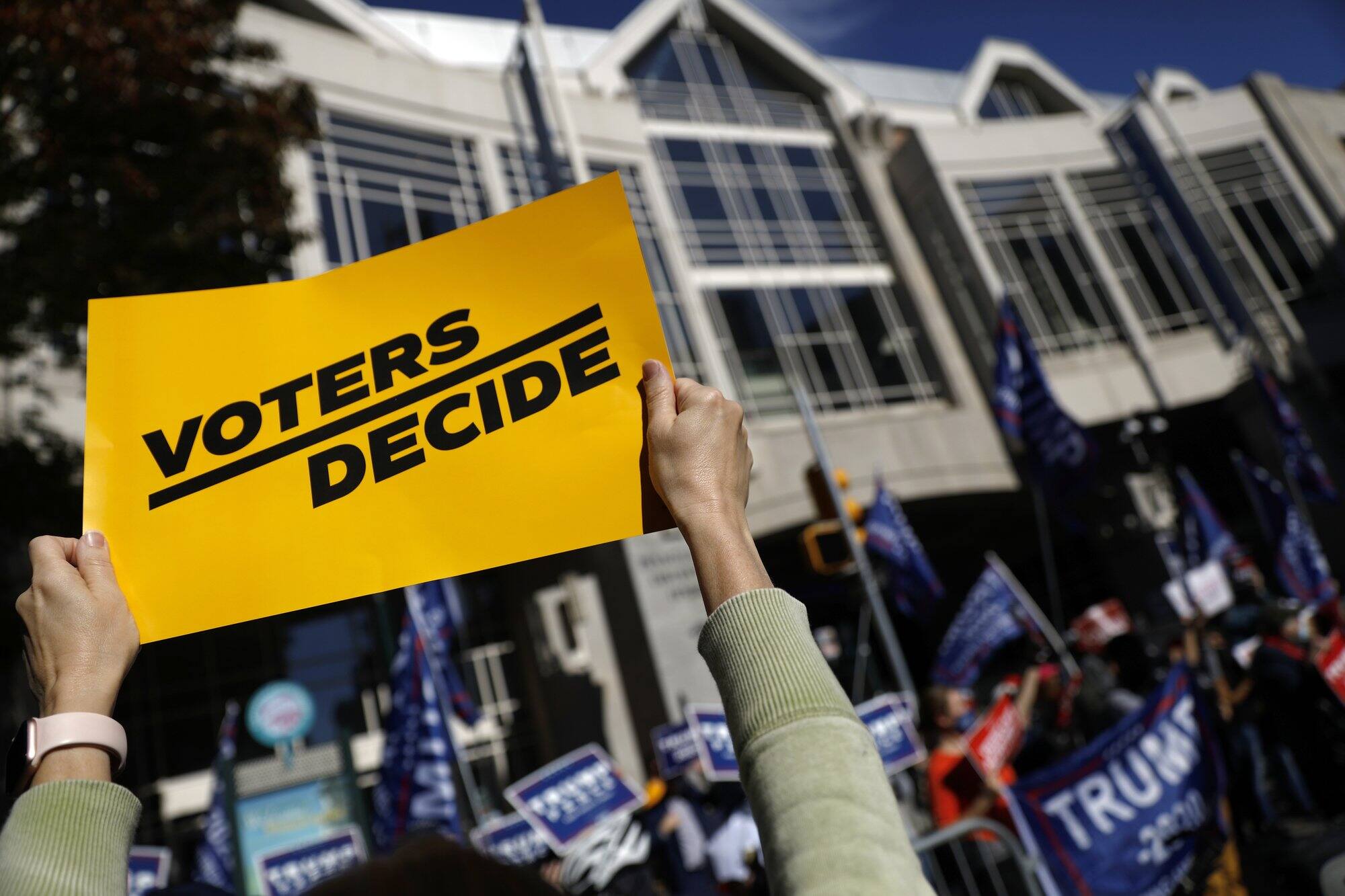 A demonstrator calling for all votes to be counted holds up a sign toward protesting supporters of President Donald Trump outside the Pennsylvania Convention Center, Thursday, Nov. 5, 2020, in Philadelphia, as vote counting in the general election continues. (Image: AP Photo)