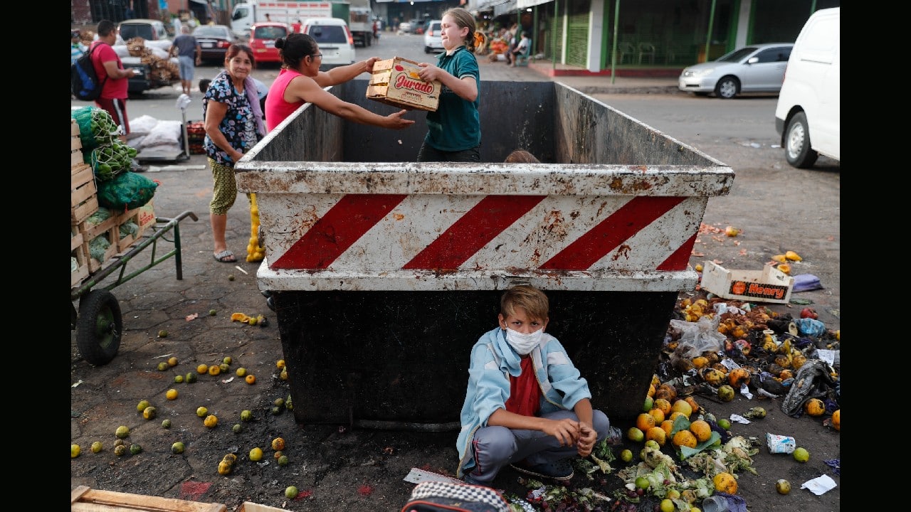 Fabian Ramirez, 11, and members of his family scavenge a trash container for discarded vegetables at the &quot;Mercado de Abasto,&quot; a market for vendors, during the fourth week of quarantine to contain the spread of the new coronavirus in Asuncion, Paraguay, April 2. (Image: AP)