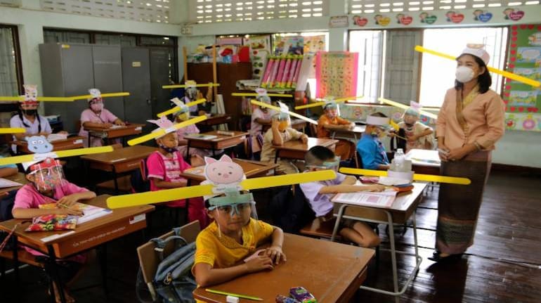 A teacher and students, wearing hats designed for space keeper, practice social distancing to help curb the spread of the coronavirus at Ban Pa Muad School in Chiang Mai, north of Thailand, on July 3, 2020. (AP Photo/Wichai Taprieu)