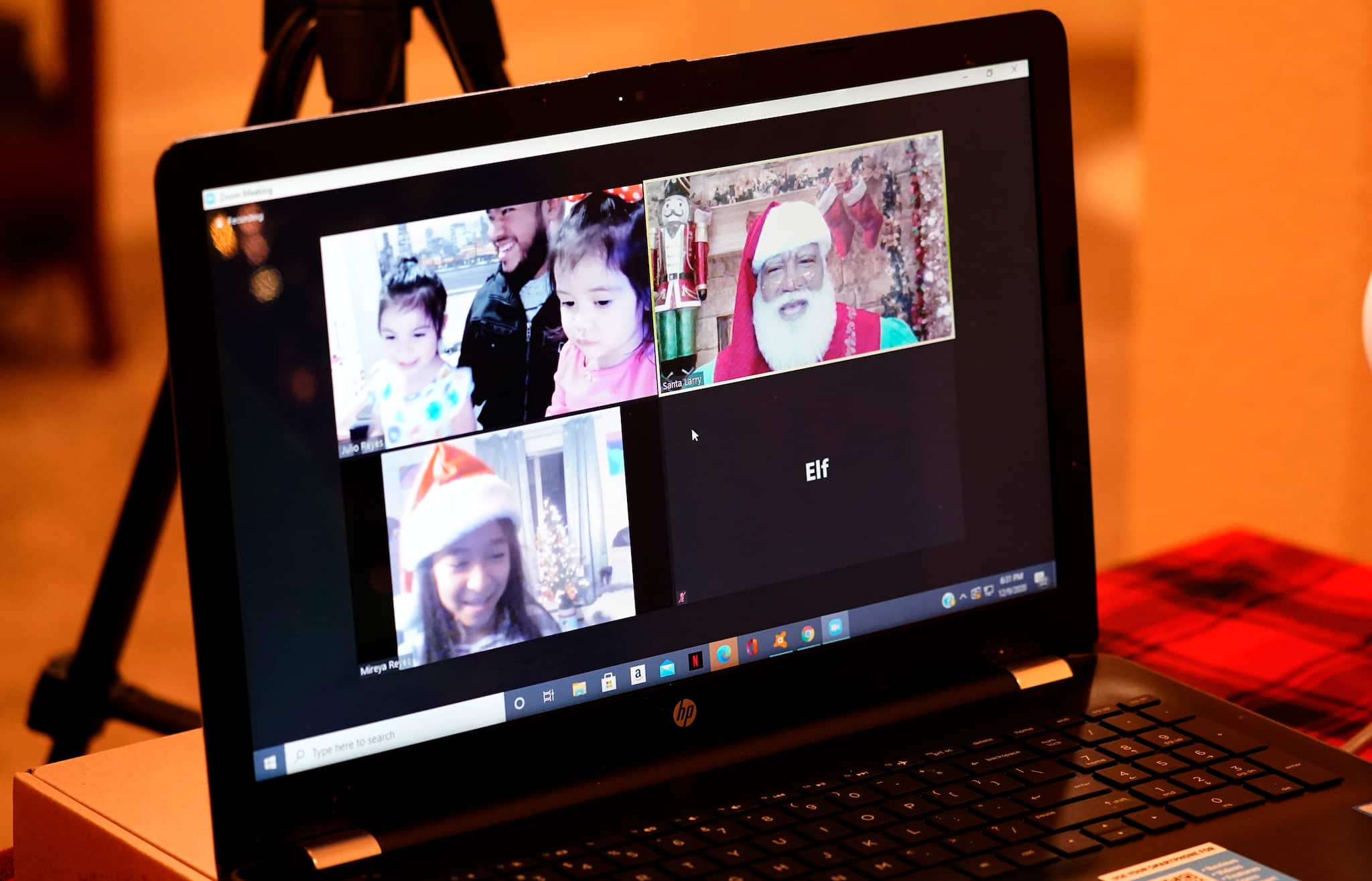 Larry Jefferson, right, portrays Santa Claus and conducts a visit via a computer screen with Raquel Anaya, bottom left, and her cousins Lexi Reyes, top left, and Luna Reyes from his home in Duncanville, Texas, on Dec. 9, 2020. The children lost a grandmother to COVID-19 recently. In this socially distant holiday season, Santa Claus is still coming to towns (and shopping malls) across America but with a few 2020 rules in effect. (AP Photo/LM Otero)