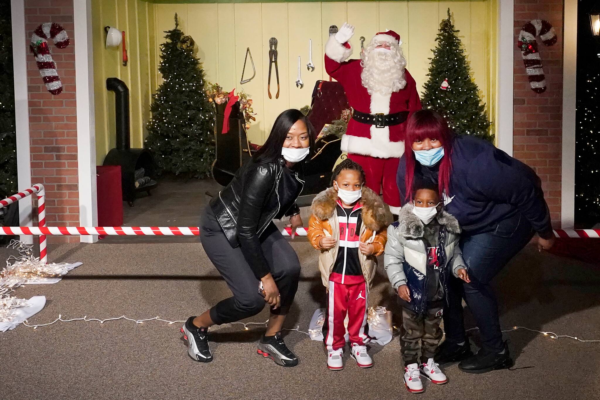 The Bell family poses for a photo with a social distant Santa as they visit Santa's Garage on the roof of a parking deck near Soldier Field in Chicago on Dec. 10, 2020. In this socially distant holiday season, Santa Claus is still coming to towns (and shopping malls) across America but with a few 2020 rules in effect. (AP Photo/Charles Rex Arbogast)