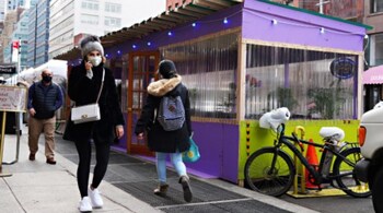 People wearing protective masks walk by a weatherized outdoor dining structure outside a restaurant on the Upper East Side as the city continues the re-opening efforts following restrictions imposed to slow the spread of coronavirus on November 19, 2020 in New York City. (PC- AFP/Cindy Ord/Getty Images)