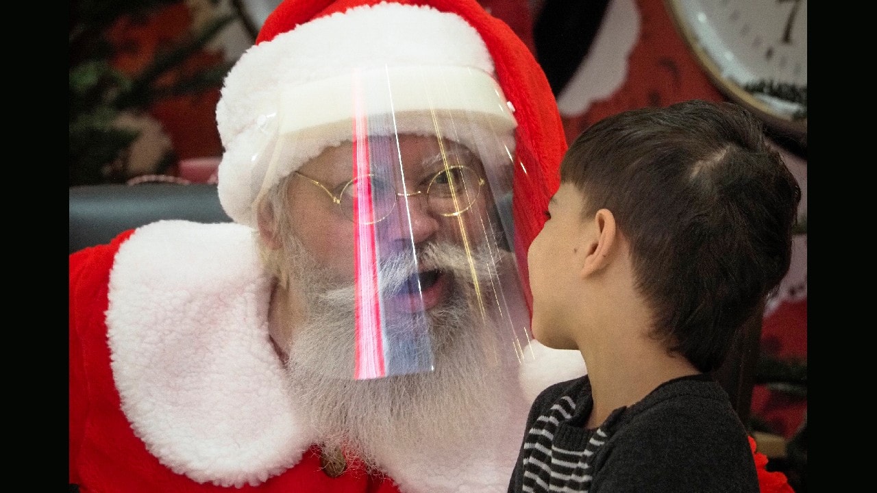 An actor dressed as Santa Claus and wearing a face mask to protect against coronavirus infection speaks with a boy during the New Year celebration in a shopping mall in St.Petersburg, Russia, January 2. (Image: AP/Dmitri Lovetsky)