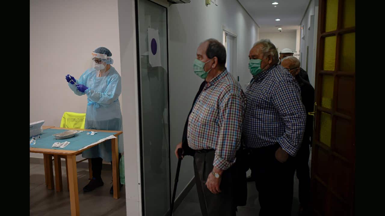 A state health worker, left, prepares a Pfizer coronavirus vaccine for residents waiting in a hall at the San Jeronimo nursing home, in Estella, around 38 kilometers (23 miles) from Pamplona, northern Spain, January 7. Spain plans to receive over 4.5 million doses of the vaccine over the next three months, enough it says to immunize just over 2.2 million people. The government estimates that this first phase will be enough to cover nursing home residents and workers, followed by health workers in general and people with disabilities. (Image: AP/Alvaro Barrientos)