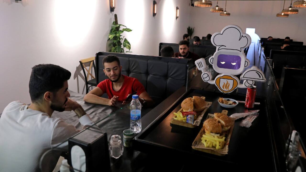 People receive their order from a robot which serves food to customers at a restaurant, amid the spread of the coronavirus disease (COVID-19), in Kerbala, Iraq November 25, 2020. (Image: Reuters)