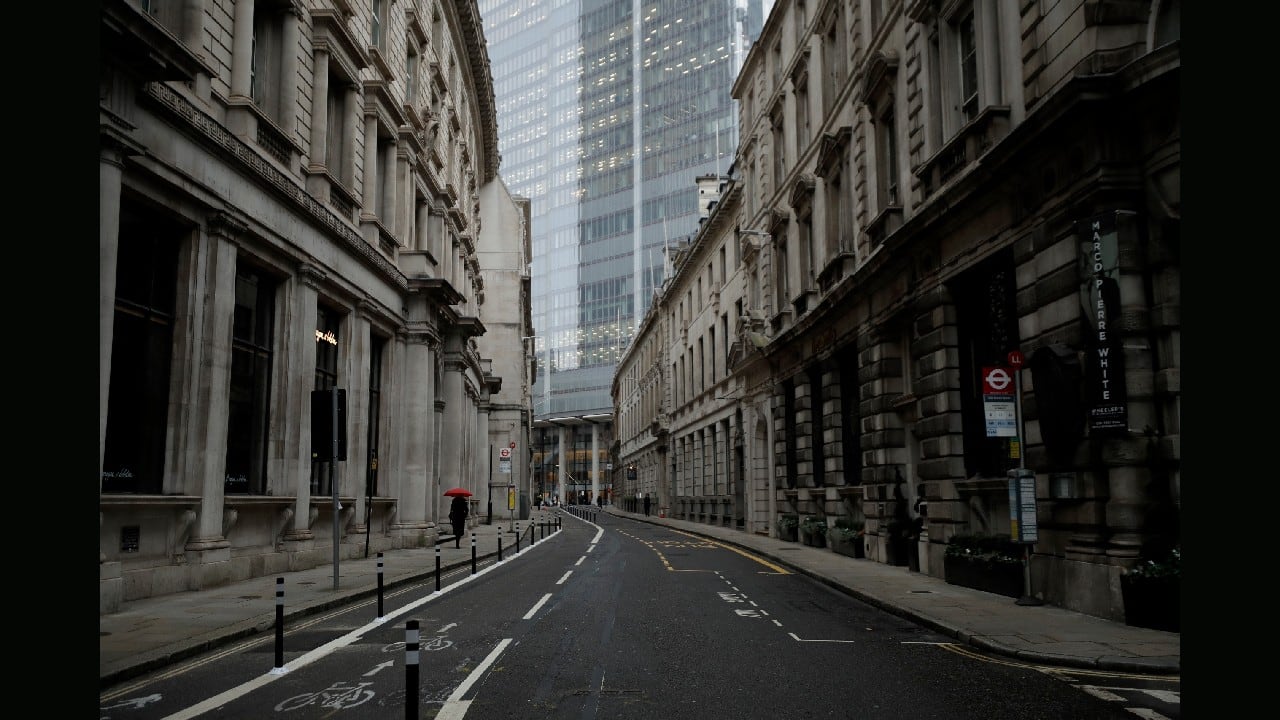 A person walks with an umbrella in light rain in the City of London financial district in London, on January 5, on the first morning of England entering a third national lockdown since the coronavirus outbreak began. Prime Minister Boris Johnson on Monday night announced a tough new stay-at-home order, as authorities struggle to stem a surge in COVID-19 infections that threatens to overwhelm hospitals around the U.K. (Image: AP/Matt Dunham)