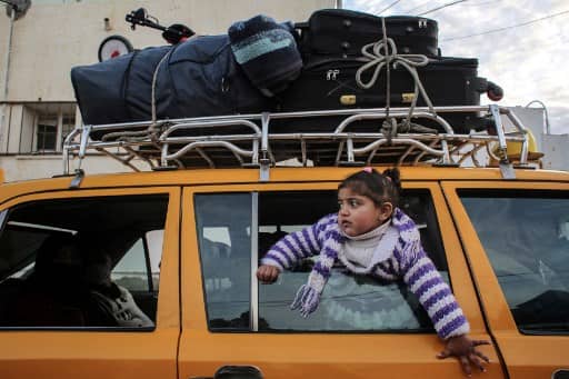 A girl looks on through the window of a vehicle whose top is loaded with suitcases, while waiting at the Rafah border crossing's departure area to travel from the Gaza Strip into Egypt, on February 9, 2021, which reopened after an Egyptian announcement to let through incoming traffic until further notice. - Egypt on February 9 opened its border crossing "indefinitely" with Gaza -- the Israeli-blockaded Palestinian enclave -- against the backdrop of Palestinian political unity talks in Cairo continue, a security source said. (Photo by SAID KHATIB / AFP)