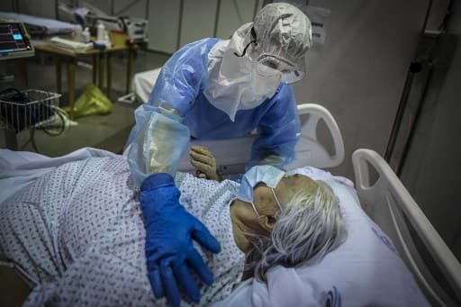 A healthcare worker attends to a patient at the Portimao Arena sports pavilion converted in a field hospital for Covid-19 patients at Portimao, in the Algarve region, on February 9, 2021. (Photo by PATRICIA DE MELO MOREIRA / AFP)