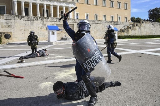 Riot police officers detain protestors during a demonstration of university students against lawmakers who are preparing to approve a plan creating a special police force to combat endemic violence in universities, in front of the Greek parliament in Athens on February 10, 2021. - Some 5,000 students gathered in Athens, a police source said, despite a recent ban on protests over 100 people to stem the spread of the coronavirus pandemic. Riot police used tear gas to disperse a small group of protesters in front of the parliament building and skirmished with club-wielding demonstrators who tried to break through their line. (Photo by ARIS MESSINIS / AFP)
