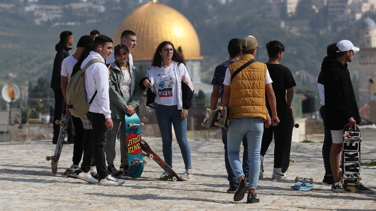 The Dome of the Rock located on the compound known to Muslims as Noble Sanctuary and to Jews as Temple Mount is seen in the background as Palestinian youths hold their skateboards while standing on a rooftop, as Israel partially lifts its third national lockdown to fight the coronavirus disease (COVID-19) crisis, in Jerusalem's Old City February 7. (Image: Reuters)