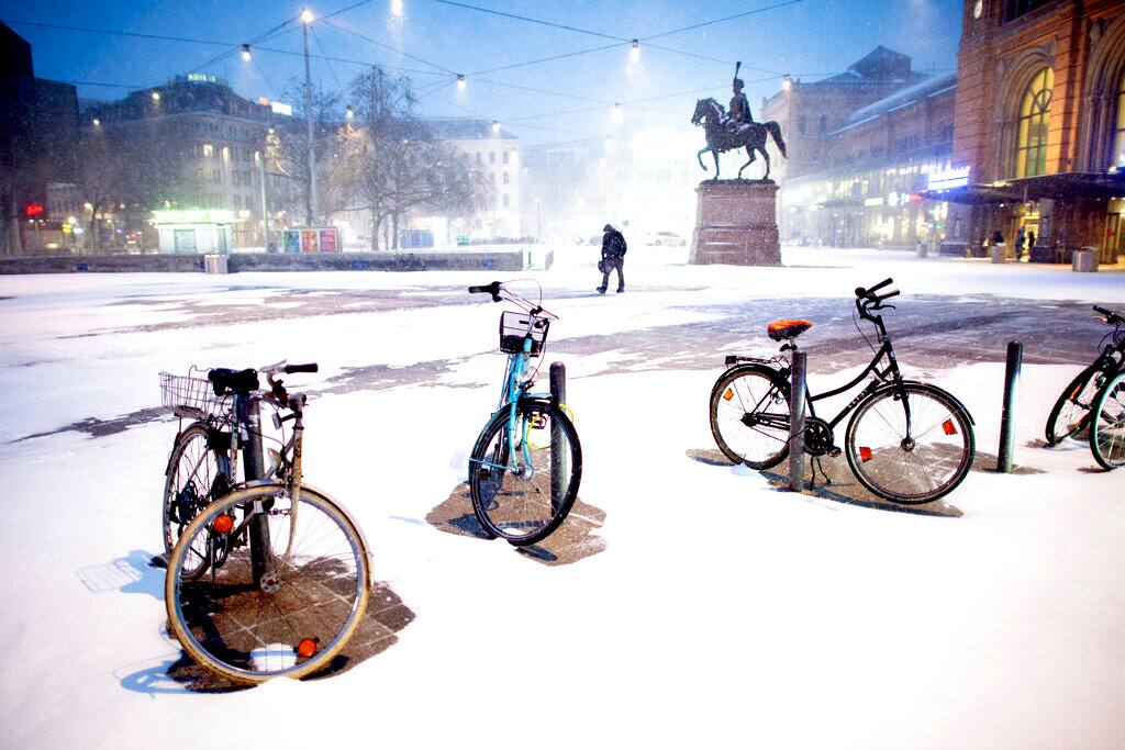 Bicycles are parked at Ernst-August-Platz in front of the main station during heavy snowfall in Hannover, Germany, Sunday, Feb. 7, 2021. (Hauke-Christian Dittrich/dpa via AP)