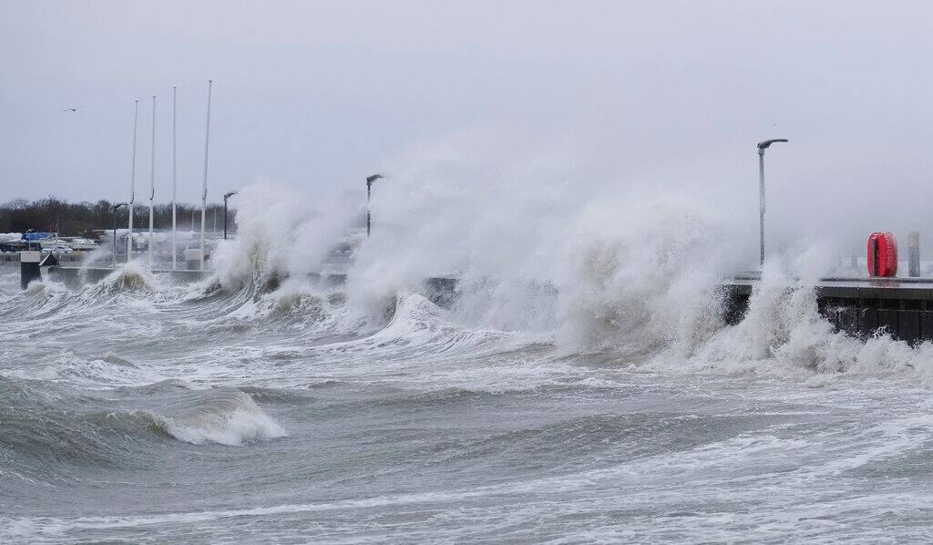 Waves crashing against the harbour wall in Strande, Germany, Sunday, Feb. 7, 2021. Squalls of up to 47 knots hit the mainland from the east. (Frank Molter/dpa via AP)