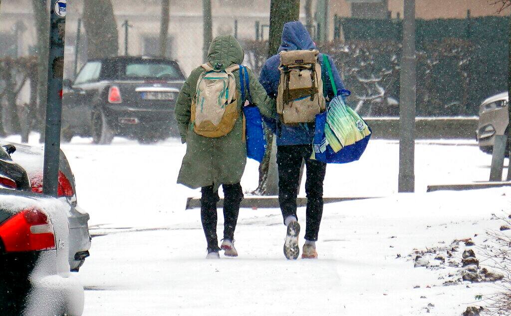 Two people walk on a snow covered side walk in Berlin, Germany, Sunday, Feb. 7, 2021. A snowstorm and strong winds pounded northern and western Germany on Sunday, forcing trains to cancel trips and leading to hundreds of road accidents. Police said 28 people were injured on icy roads. (AP Photo/Michael Sohn)