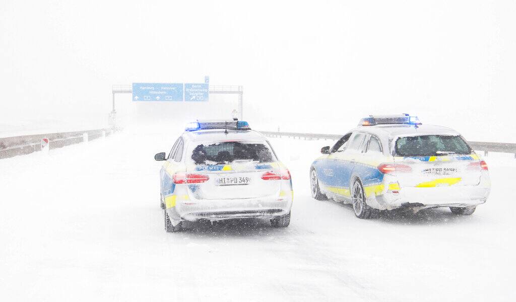 Police vehicles stand on the closed A7 motorway at the Salzgitter interchange in Bockenem, Germany, Sunday, Feb. 7, 2021. Police have closed the A7 between Bockenem and the Salzgitter interchange due to snow drifts and poor visibility caused by the snowstorm in the northbound direction. (Julian Stratenschulte/dpa via AP)