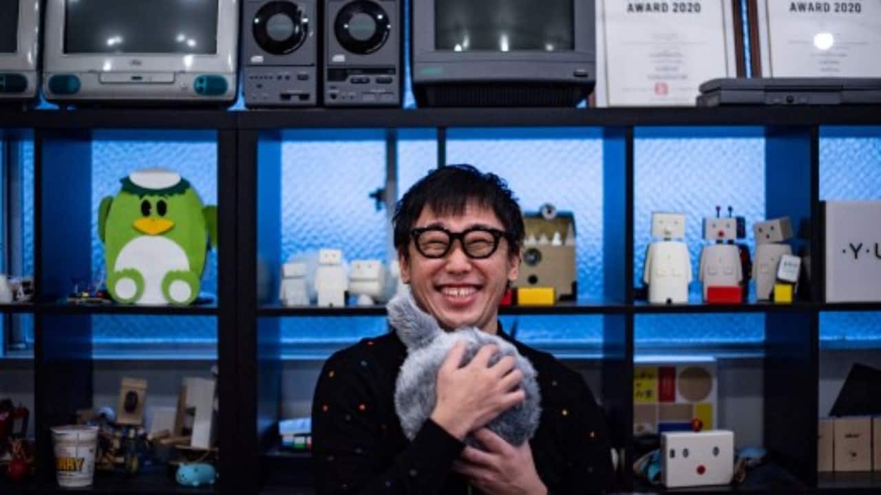 Shunsuke Aoki hugging robotic cushion Qoobo in a studio in Tokyo. (PC-Philip FONG/AFP)