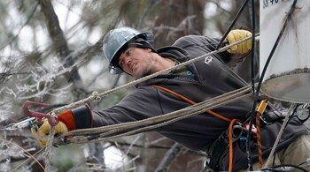 Lineman Sean Gregory stretches for a cable as he repairs a transformer in Jackson, Mississippi Februaty 18, 2021. Gregory, who is employed by GPC Corp., an electrical utility contractor, is one of a number of specialists assisting Mississippi power utility company Entergy in restoring electricity to its customers, following a mid-month ice storm. (PC-AP Photo/Rogelio V. Solis)