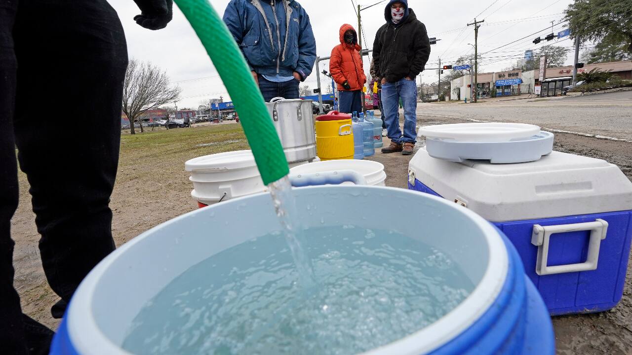A water bucket is filled as others wait in near freezing temperatures to use a hose from public park spigot Thursday, Feb. 18, 2021, in Houston. (PC-AP Photo/David J. Phillip)
