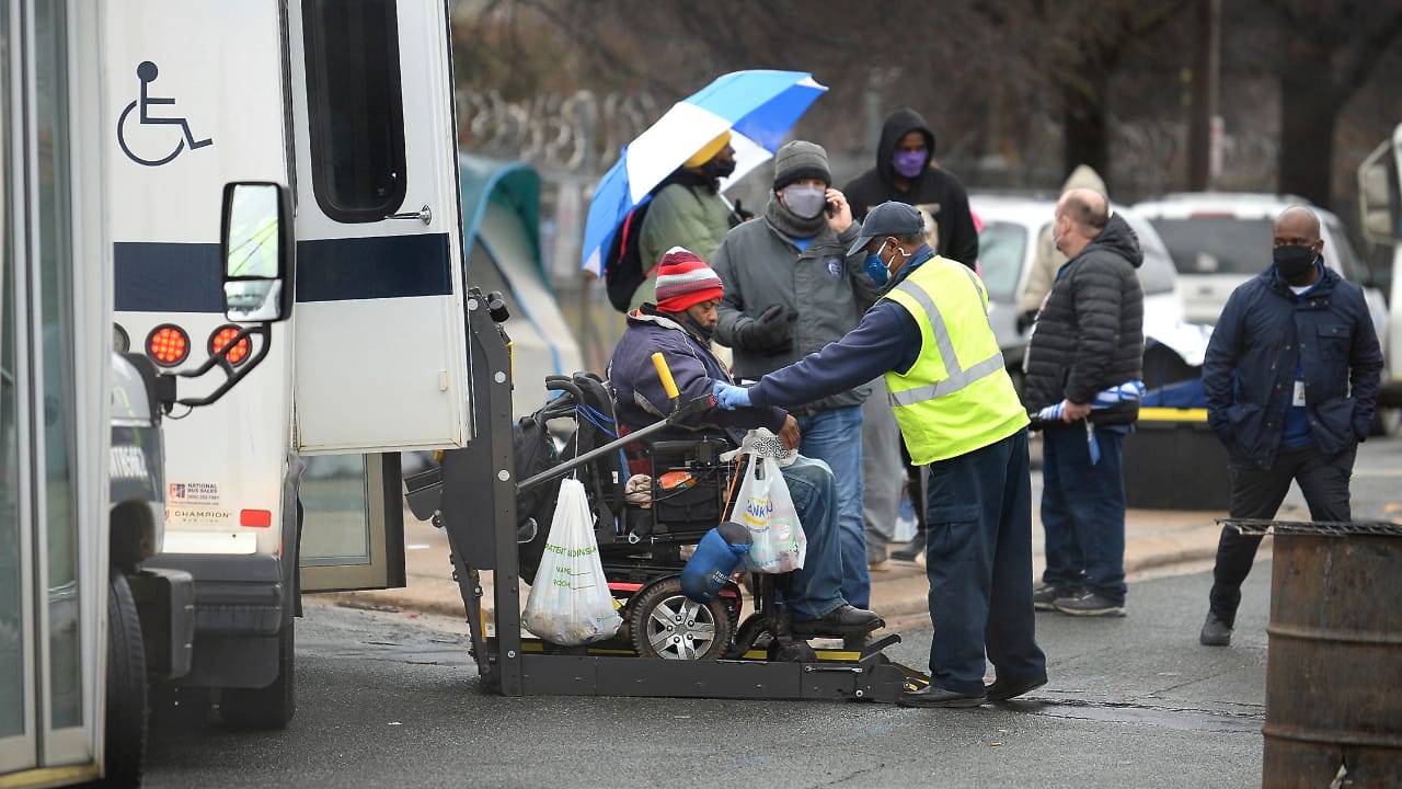 A man is loaded onto a bus for a trip to a hotel on February 18, 2021 in Charlotte, N.C. Residents of the homeless encampment &quot;Tent City&quot; are being required to vacate the area within 72 hours after health risks from rodent infestation was found in the area. (PC-Jeff Siner/The Charlotte Observer via AP)