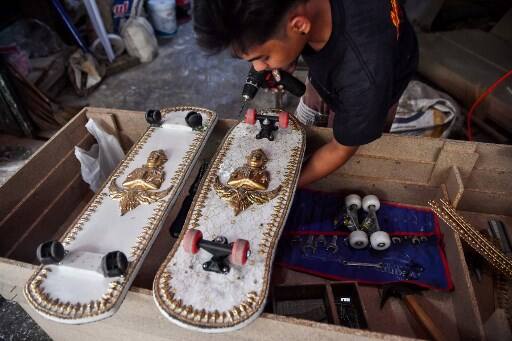 &quot;Some kids have never ever heard of a skateboard before so we want to make these casket skateboards as close to the real boards as possible. &quot;That way they could play and smile a little bit from all the fun.&quot; This photo taken on March 19, 2021 shows an employee from the Burapha coffin shop putting wheels on skateboards, made from wood used for coffins, in Bangkok. (Photo by Lillian SUWANRUMPHA / AFP)