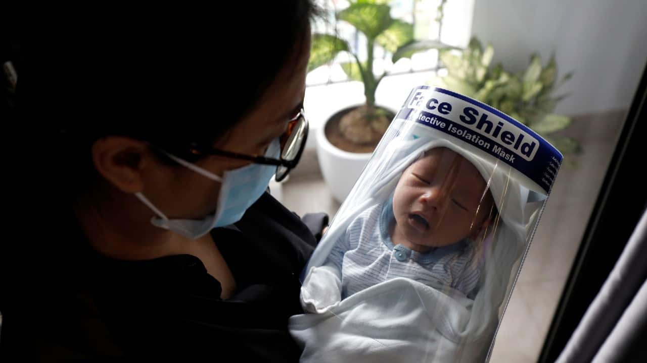 Newborn baby Phuc An, wearing a protective face shield, is carried by his mother Nguyen Huyen Trang, a local bank auditor, as he receives vaccinations at home in Hanoi, Vietnam April 13, 2020. Phuc An was born at Vinmec hospital in Hanoi on April 1, when the Southeast Asian country started its strict restrictions on movement to contain the spread of the coronavirus. The lockdown put most of the social and economic activities throughout the country on hold, but life must go on, and giving birth couldn't be delayed. (Image: Reuters)