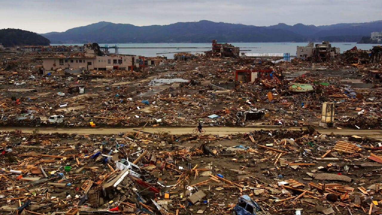 A survivor of the earthquake and tsunami rides his bicycle through the leveled city of Minamisanriku, in northeastern Japan, four days after the Tsunami, March 15, 2011. (Image: AP)