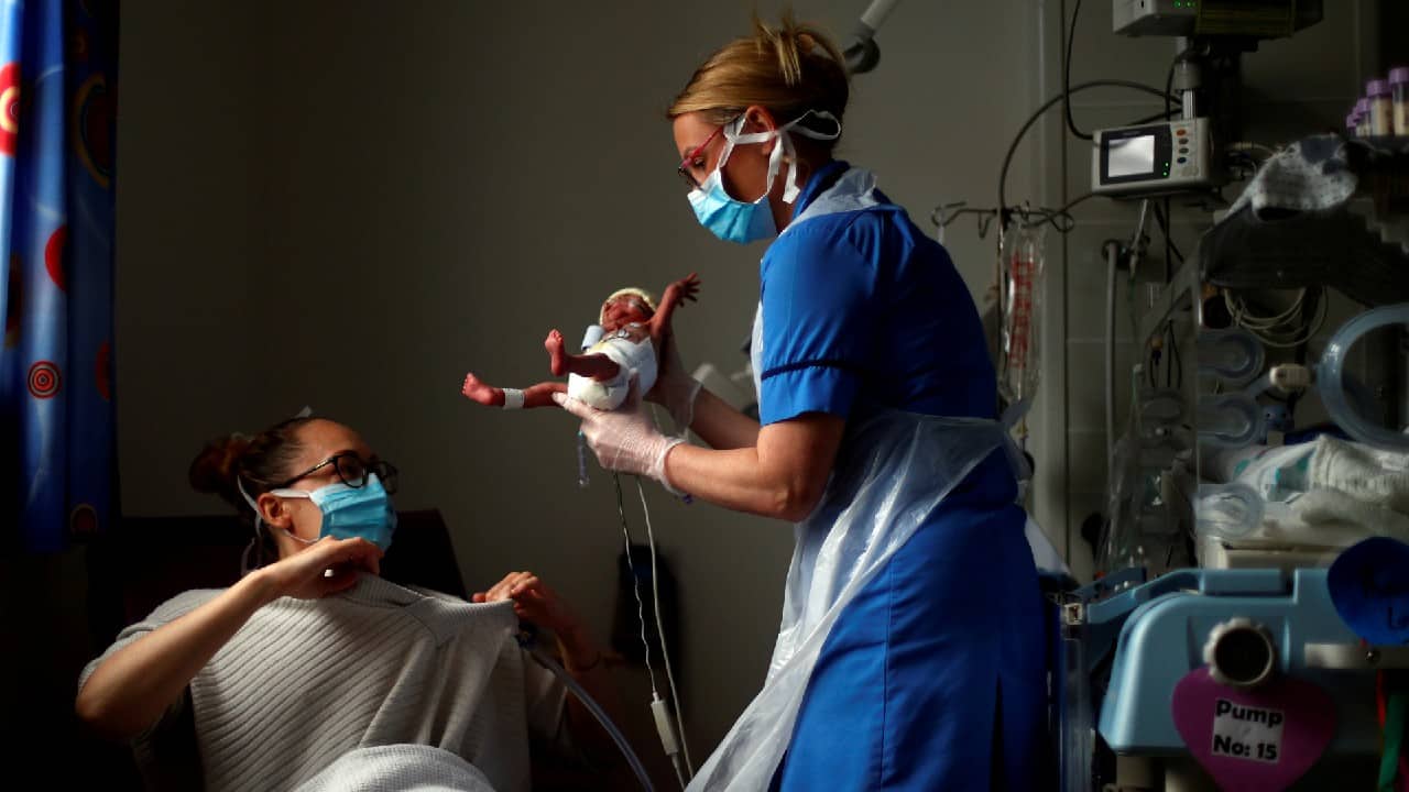 Neonatal nurse Kirsty Hartley carries premature baby Theo Anderson to his mother Kirsty Anderson in the Neonatal Intensive Care Unit at the Lancashire Women and Newborn Centre at Burnley General Hospital in East Lancashire, in Burnley, Britain May 15, 2020. (Image: Reuters)