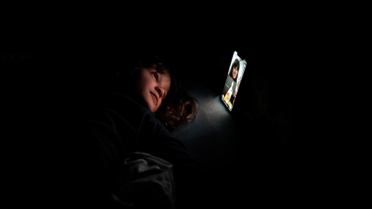 Bianca Toniolo, 3, smiles as she has a video call with her mother Chiara Zuddas, 32, who is self-isolating in a bedroom after having contact with someone with coronavirus, in this picture taken by Bianca's father who is also in quarantine at home with his family in San Fiorano, Italy, February 9, 2021. (Image: Reuters)
