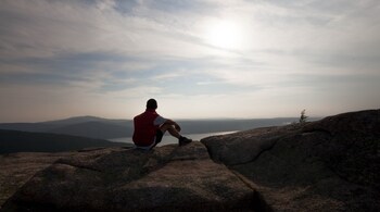 A hiker enjoys a view of Somes Sound from Parkman Mountain in Acadia National Park, near Bar Harbor, Maine, July 8, 2014. As coronavirus vaccinations ramp up and social distancing protocols become more likely to recede, now is the time to start looking ahead, to spring and summer excursions in the great outdoors. (PC-Sara Fox/The New York Times)