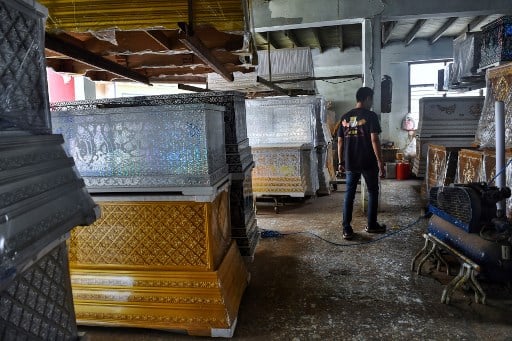 As the popularity of board sports exploded in Thailand, and the price of a skateboard skyrocketed, Anusorn Yungyearn decided to breathe new life into some of the wooden caskets he had lying around his Bangkok workshop. This image shows coffin-maker Anusorn Yungyearn looking at his stock of coffins. (Image: AFP)