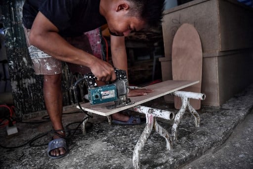 &quot;I want to give the kids who don't really have much chance in life an opportunity to skate,&quot; said the 30-year-old. &quot;I also don't want them to ask their parents to buy one for them since the cost of it is really high.&quot; Here an employee from the Burapha coffin shop cutting out a skateboard, made from wood used for coffins. (Image: AFP)