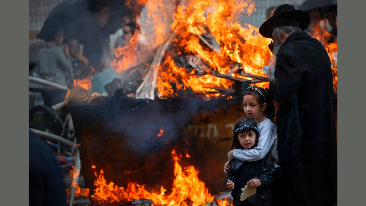 As yellow-orange flames crackle nearby, two girls embrace. One holds a piece of bread; around them, Israeli ultra-Orthodox Jews burn leavened foodstuffs that are forbidden during Passover as part of the commemoration of the Israelites’ exodus from Egypt. (Image: AP) As yellow-orange flames crackle nearby, two girls embrace. One holds a piece of bread; around them, Israeli ultra-Orthodox Jews burn leavened foodstuffs that are forbidden during Passover as part of the commemoration of the Israelites’ exodus from Egypt. (Image: AP)